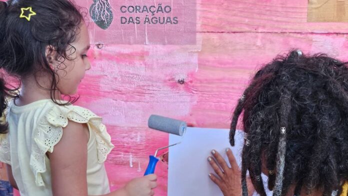 Mulheres e meninas carregando recipientes de água em uma área rural, evidenciando a desigualdade no acesso ao recurso.