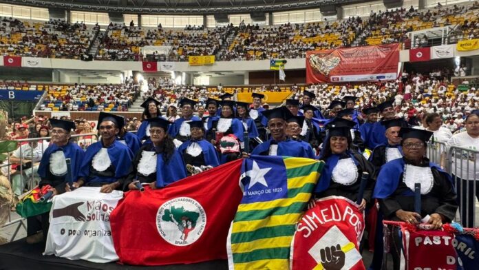 Grupo de pessoas sorridentes em evento de formatura, vestindo becas e celebrando a conclusão do ciclo de alfabetização.