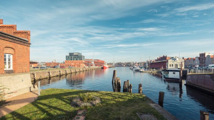 Baleia-jubarte parcialmente submersa em águas rasas, cercada por equipes de resgate em botes próximos à costa.