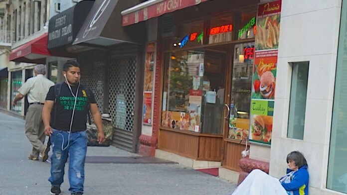 Membros da banda Rush no palco, iluminados por luzes de show, tocando instrumentos diante de uma plateia vibrante.