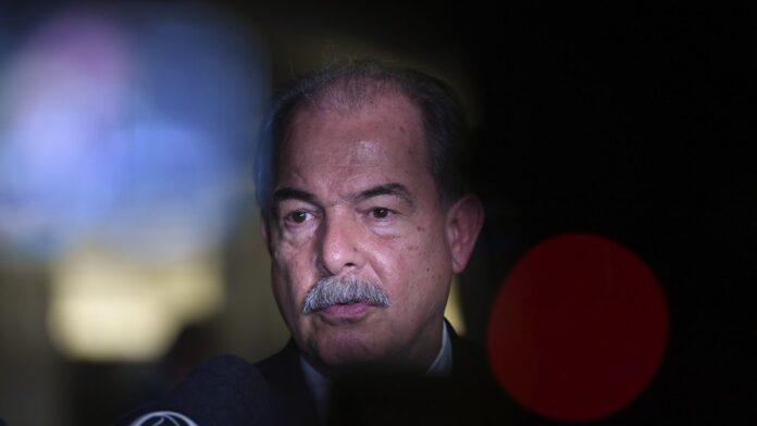 Interior de fábrica moderna com braços robóticos e tecnologia de automação em linha de produção iluminada.