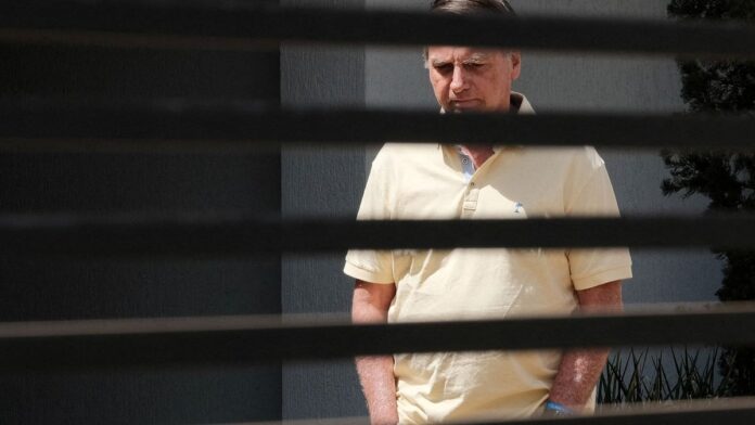 Jair Bolsonaro, de terno e gravata, posa para foto oficial com fundo desfocado em tons neutros.