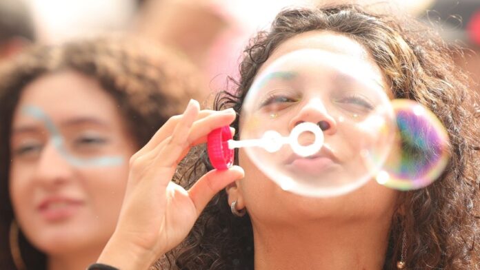 Mapa mundi com destaque no Brasil, cercado por ícones de sorrisos e bandeiras de países.