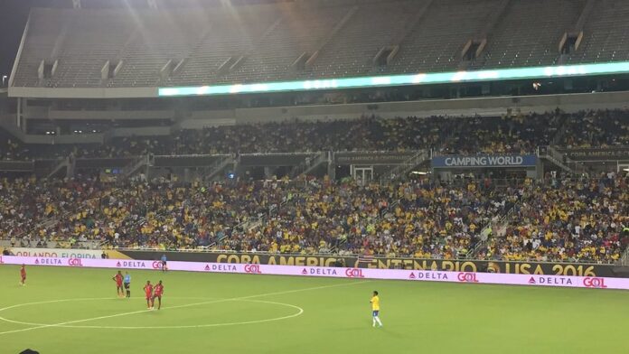 Jogadores da seleção brasileira em campo durante partida de futebol, com foco na movimentação e uniforme amarelo.