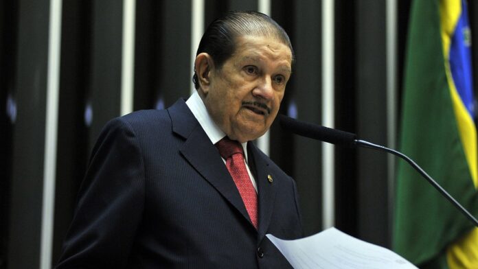 Ciclistas em ritmo de competição percorrem estrada asfaltada em Benevides, sob luz do dia.