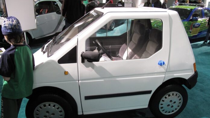 Fileira de cinco carros populares compactos de cores variadas estacionados lado a lado em um cenário urbano moderno.