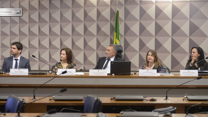 Jovens em uma sala de aula moderna, focados em atividades práticas de capacitação profissional em computadores.