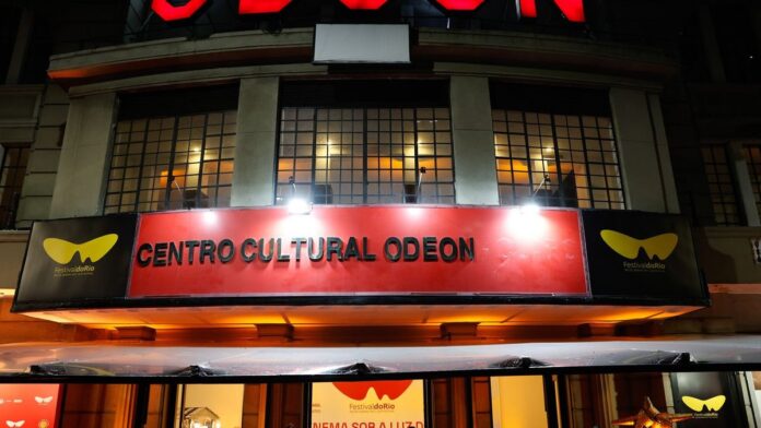 Fachada histórica e iluminada do Cine Odeon, no centro do Rio de Janeiro, com letreiro em neon à noite.