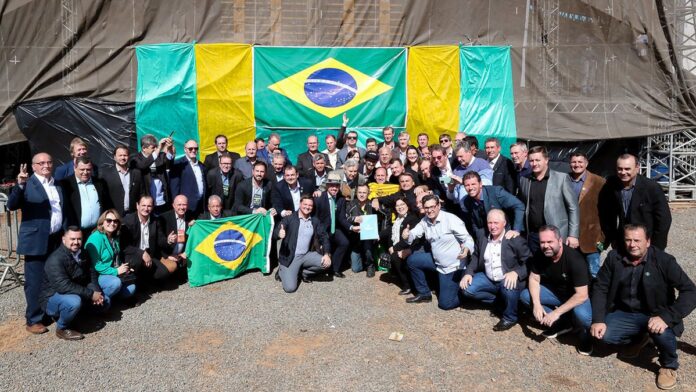 Colheitadeira percorre vasto campo de soja sob céu aberto, dando início ao processo de colheita no Rio Grande do Sul.