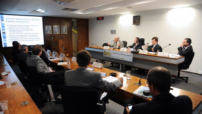 Dirigentes de clubes de futebol sentados em mesa de reunião, em ambiente formal e iluminado.