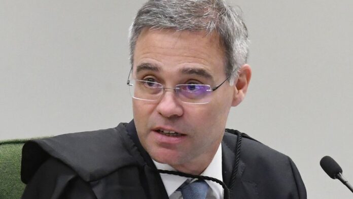 Ministro André Mendonça sentado em sua mesa de trabalho no STF, durante sessão plenária.