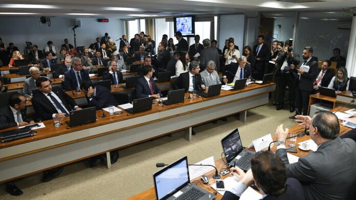 Mãos de executivos analisando documentos financeiros e gráficos complexos em uma mesa de escritório moderna.