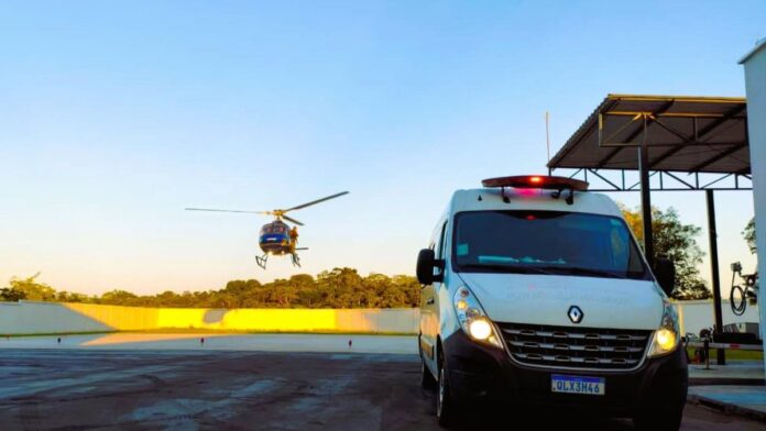 Equipe do SAMU e Ciopaer transporta criança indígena em maca para helicóptero em área de floresta.