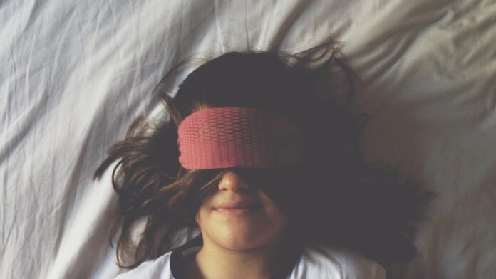 Os integrantes da banda DMA’s tocando instrumentos em um show com iluminação cênica azul e roxa.