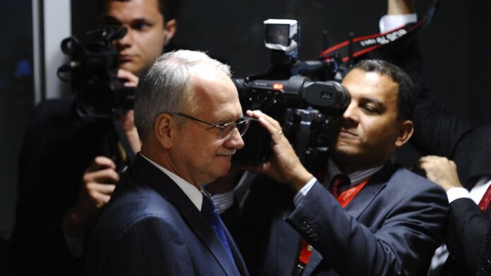 Foto do ministro Edson Fachin em seu gabinete, posicionado à frente de bandeira do Brasil, durante sessão do STF.