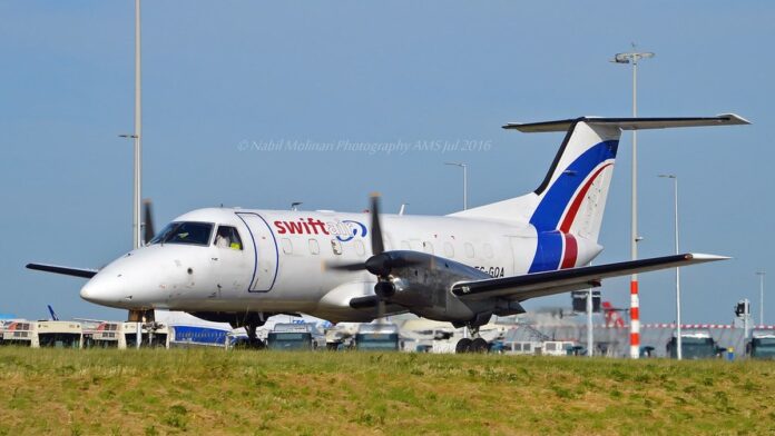 Avião comercial da Embraer em voo, visto de lado contra um céu azul limpo.