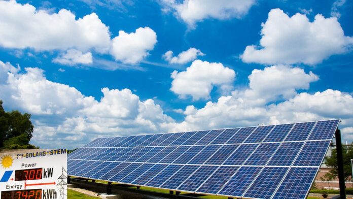 Painéis solares fotovoltaicos refletindo o céu azul em uma ampla usina solar em campo aberto.