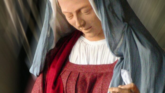 Foto de um reservatório de água com nível baixo, mostrando solo rachado e seco ao redor de uma represa sob sol forte.