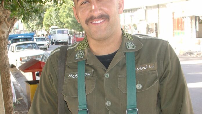 Soldados americanos em zona de conflito observam um horizonte empoeirado com escombros de construções ao fundo.