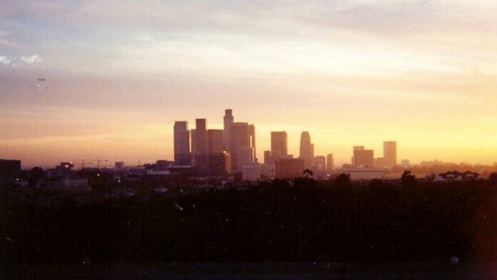 Barragem de concreto e reservatório de água em região árida, sob céu azul.