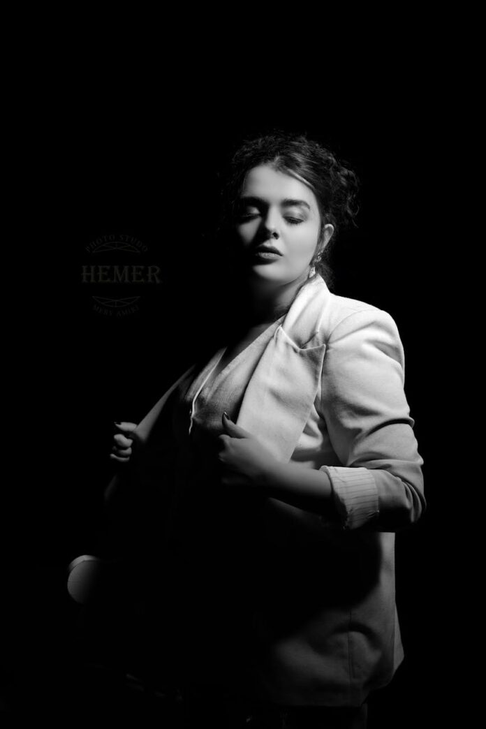 Retrato elegante em preto e branco de uma mulher em pose pensativa usando um blazer.