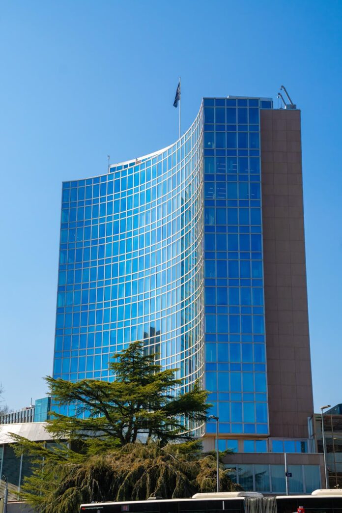 O alto edifício de vidro da OMPI, refletindo o céu azul, é um símbolo de inovação e propriedade intelectual em Genebra.