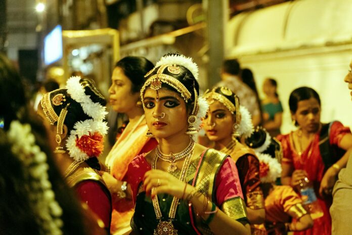 Uma vibrante cena de rua com dançarinas de Bharatanatyam em trajes tradicionais à noite em Guruvayur, Índia.