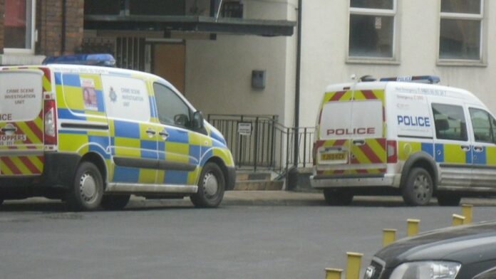 ford-transit-city-el-trico-estreia-na-europa-com-f Furgão elétrico Ford Transit de cor branca estacionado em uma rua urbana moderna durante o dia.