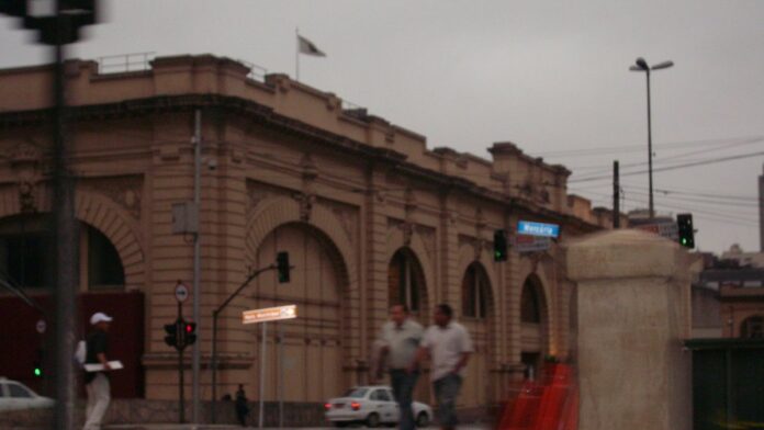 Jogadores de futebol em campo com uniforme azul e amarelo disputando a bola em estádio lotado em São Paulo.