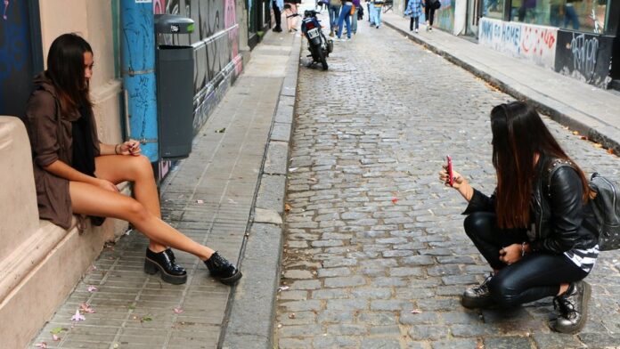Piloto Franco Colapinto posa ao lado de um carro de Fórmula 1 em uma pista de corrida, sob luz brilhante.