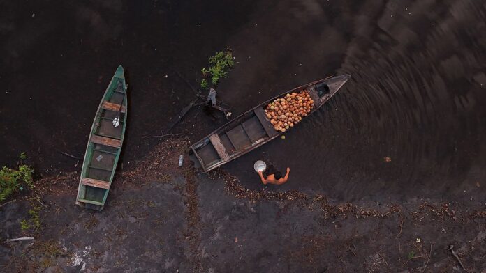 Caminhão de entrega de botijões de gás azul com logomarca, parado em rua residencial durante serviço de distribuição.