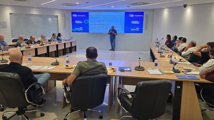Representantes do governo e empresários conversam em evento na Fieac, com banners institucionais ao fundo.