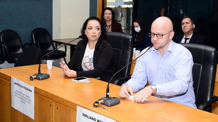 Equipe médica atendendo pacientes em sala de espera lotada de hospital durante mutirão de saúde.