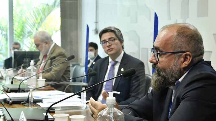 Agentes ambientais inspecionando grande quantidade de peixes apreendidos em barco.