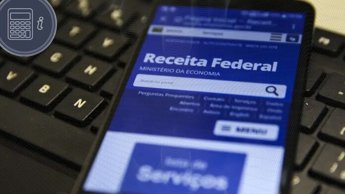 Pessoa em frente a um computador analisando documentos e formulários do Imposto de Renda com expressão de dúvida.