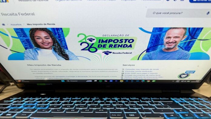 Pessoa em um escritório usando computador para preencher formulário do Imposto de Renda no portal da Receita Federal.