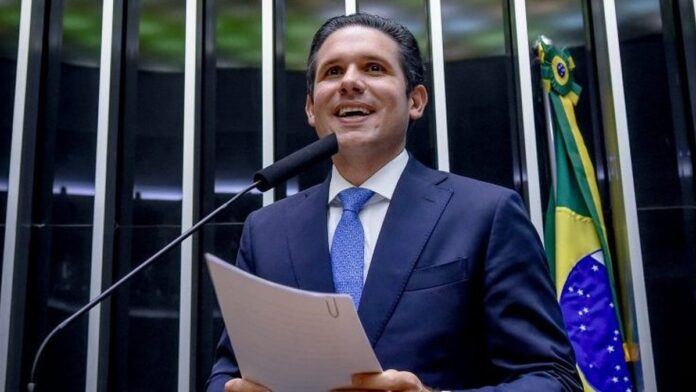 Mãos sobre um teclado de piano iluminado por luzes digitais em tons de azul e roxo, simbolizando tecnologia e música.