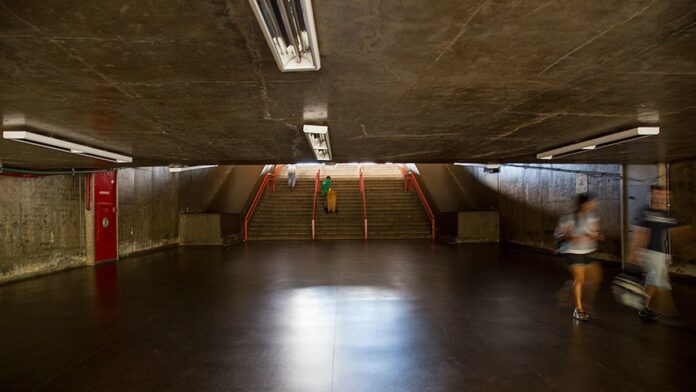 Interior de um ônibus moderno com painel digital exibindo rotas e passageiros utilizando smartphones durante a viagem.