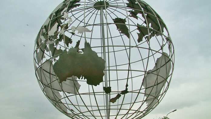 Trem de VLT moderno circulando em trilhos em uma área urbana arborizada durante o dia.