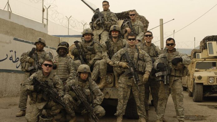 jornalista-dos-eua-sequestrada-em-bagd-e-iraque-an Jornalista vestindo colete de imprensa caminha por rua movimentada de Bagdá, ladeada por prédios de arquitetura árabe.