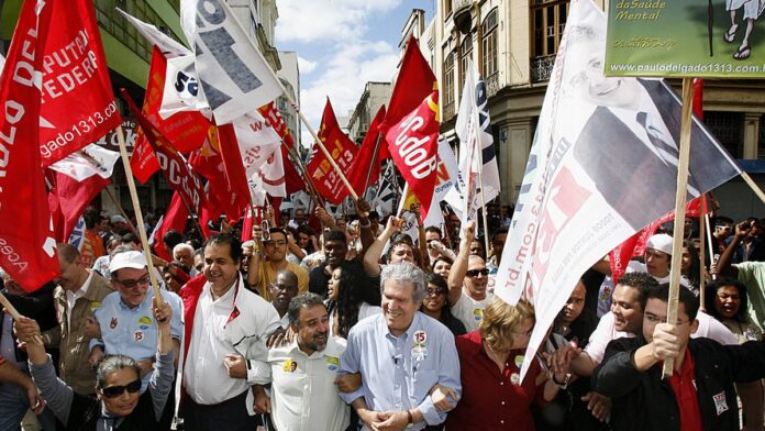 Ruas de Juiz de Fora cobertas por lama e escombros, com moradores limpando casas após os temporais.