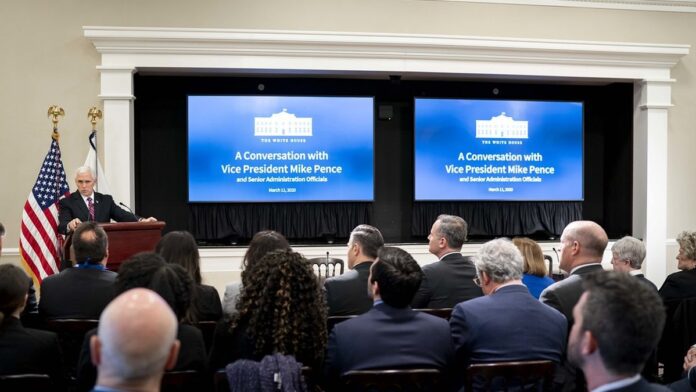 Grupo de gestores municipais em reunião, discutindo documentos e tablets em uma mesa de escritório.
