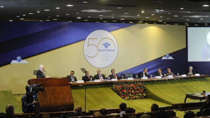 Foto de produtos eletrônicos da Apple e garrafas de vinho organizados em uma mesa, prontos para leilão.