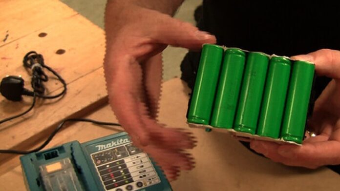 limite-de-carga-em-80-pode-reduzir-autonomia-do-ce Smartphone sobre uma mesa com o cabo de carregamento conectado e um ícone de bateria carregada na tela.