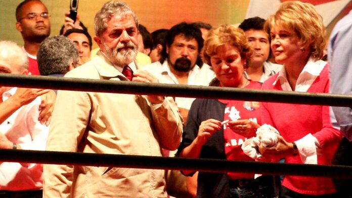 Presidente em evento sobre energia apontando para gráficos de petróleo.