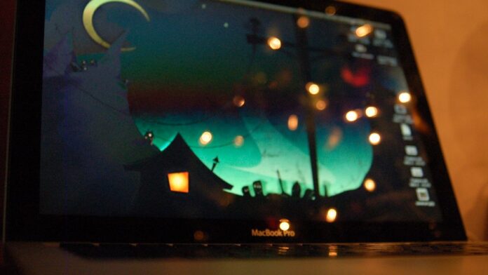 m5-macbook-pro-vale-upgrade-do-m1-o-que-os-n-meros Dois modelos de MacBook Pro abertos lado a lado sobre uma mesa, exibindo detalhes do design e telas em ambiente iluminado.