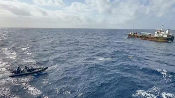 Navio-tanque de grande porte à deriva em mar aberto, sendo rebocado por embarcação da Marinha do Brasil.