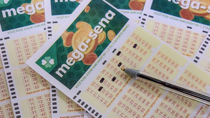 Mãos segurando um volante da Mega-Sena preenchido ao lado de uma urna transparente com várias bolas numeradas dentro.