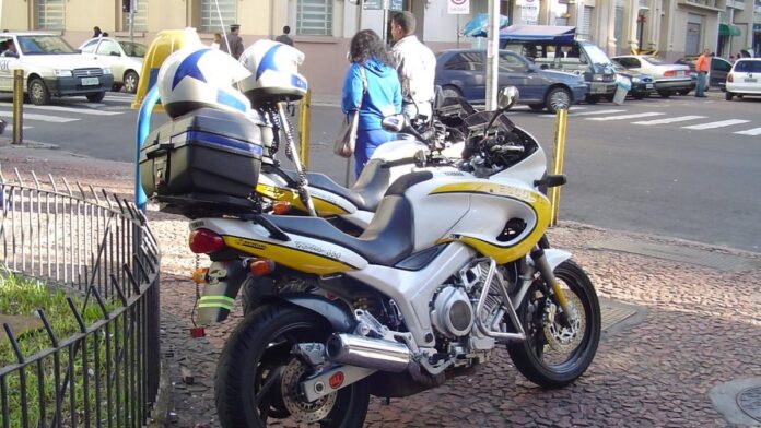 Viatura da Polícia Militar parada em via pública isolada com fita zebrada, durante registro de ocorrência.