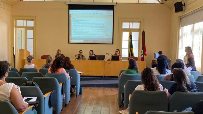 Reunião com pessoas em mesa de escritório discutindo políticas públicas voltadas à infância e juventude.